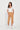 A woman modeling a pair of tan cropped cargo pants with a white scoop-neck t-shirt by Verge and white sneakers, standing against a plain white studio background.
