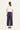 A woman viewed from the back wearing a white short-sleeve top and navy wide-leg cropped pants by Verge, standing against a plain white studio background.