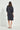 Woman wearing a dark blue dress by Verge on a white background