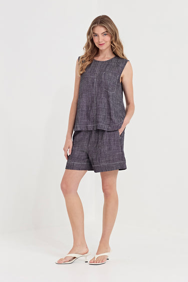 A woman modeling a matching sleeveless tank and shorts set by Vergein a dark gray textured fabric, paired with white slide sandals, against a plain white studio background.