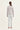 A woman viewed from the back wearing a light gray quilted long-sleeve jacket and white pants by Verge, against a plain white studio background.
