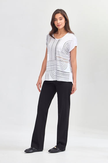 A woman modeling a white short-sleeve top with a black geometric stripe pattern, paired with black wide-leg pants by Verge and black flats, against a light gray studio background.