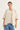 A woman modeling a light beige linen-blend vest with a V-neck and front buttons, styled over a matching beige top and blue jeans by Verge, against a plain off-white studio background.