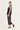A woman modeling a sleeveless black top and black wide-leg cropped pants by Verge with white floral embroidery, paired with black slingback heeled sandals, against a plain off-white studio background.
