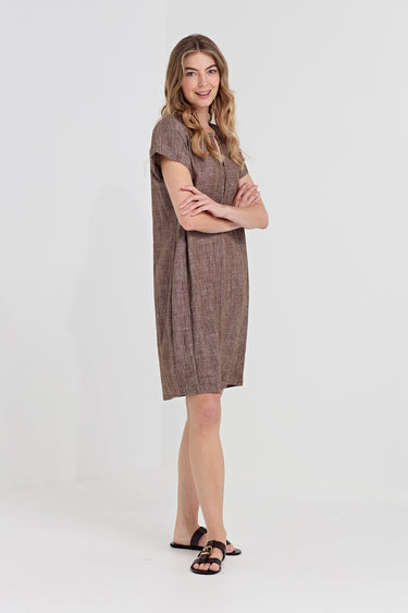 A woman modeling a brown textured short-sleeve shift dress with a subtle plaid pattern by Verge, paired with black slide sandals, against a plain white studio background.