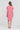 A woman viewed from behind wearing a short-sleeve pink linen dress by Verge with a gathered neckline, standing against a plain white studio background.