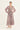A woman modeling a long-sleeved midi dress with a dusty rose and gray abstract floral pattern by Verge, standing against a plain off-white studio background.