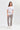 A woman modeling a white short-sleeve t-shirt with a gray leaf pattern and beige snakeskin print pants by Verge, paired with white sneakers, against a light gray studio background.