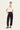 Woman wearing a white top and black Homeland Pants by Verge on a white background