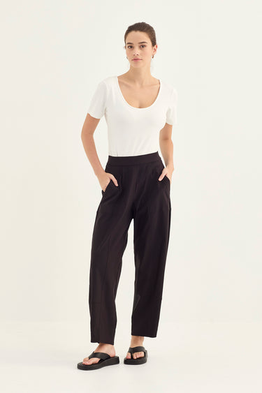 Woman wearing a white top and black Homeland Pants by Verge on a white background