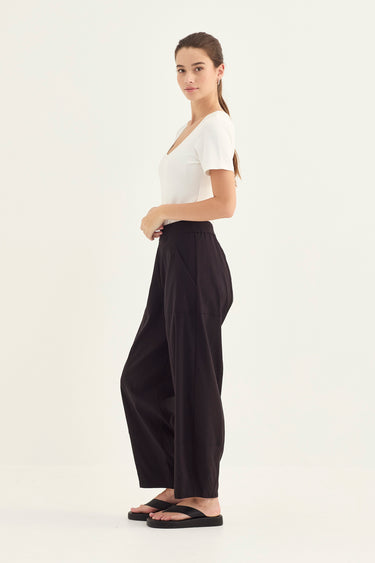 Woman wearing a white top and black Homeland Pants by Verge on a white background