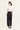 Woman wearing a white top and black Homeland Pants by Verge on a white background