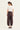 Woman wearing a white top and Chocolate Homeland Pants by Verge on a white background