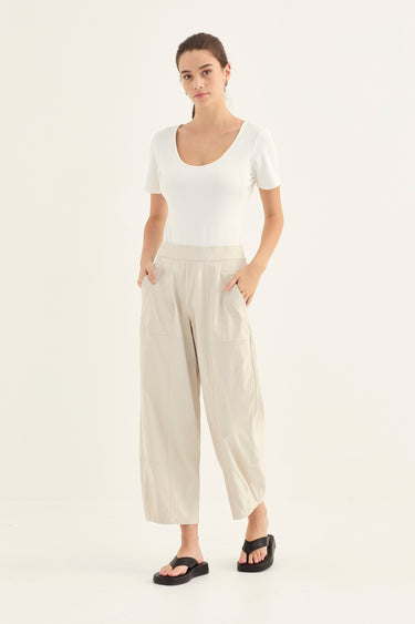 Woman wearing a white top and Putty Homeland Pants by Verge on a white background