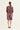 A woman viewed from the back wearing a knee-length patterned dress by Verge with three-quarter sleeves and beige heels, against a plain light background.