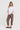 A woman modeling a white short-sleeve top and brown textured cropped pants by Verge with dark brown sandals, standing against a plain light background.