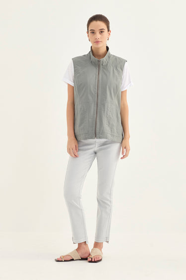 A woman modeling a light gray sleeveless button-front vest over a white t-shirt, paired with light gray pants by Verge and beige flat sandals, against a plain white studio background.
