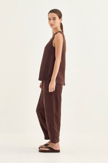 A woman modeling a dark brown sleeveless tank and matching wide-leg pants set by Verge, shown in profile against a plain light background.