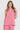 A woman modeling a sleeveless pink linen top by Verge and matching pants against a light gray studio background.