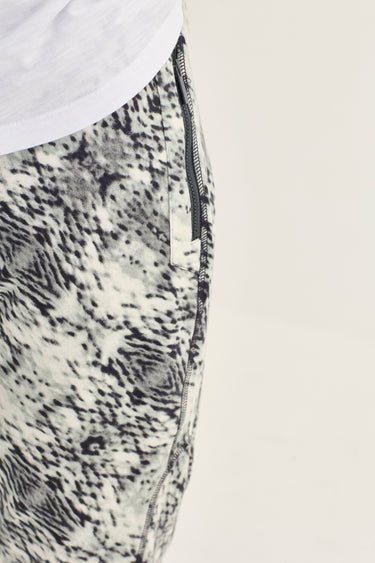 Close-up of a garment with a snake print pattern by Verge, featuring a visible black zipper detail and a white fabric section at the top, set against a plain light background.