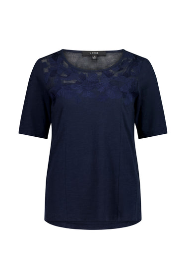 A navy blue short-sleeve top by Verge with a sheer floral lace overlay across the chest and shoulders, shown against a plain white background.