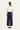 A woman viewed from behind wearing a white short-sleeve top and navy wide-leg cropped pants by Verge, standing against a plain light background.