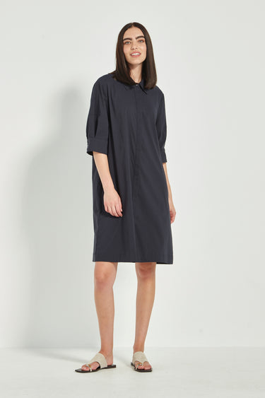 Woman wearing a dark blue dress by Verge on a white background