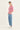 A woman modeling a red and white striped short-sleeve t-shirt, paired with light blue jeans by Verge and white sneakers, standing against a plain white studio background.
