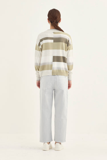 Person wearing a striped sweater and white pants by Verge on a white background