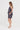 A woman modeling a sleeveless dark gray and black textured linen-like tank and shorts by Verge in ink colour, shown in profile against a plain white studio background.