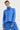 A woman modeling a bright blue cropped quilted zip-up jacket with a high stand-up collar, paired with matching blue sweatpants by Verge, against a plain light background.