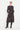 Woman wearing a black patterned dress from Verge with black boots on a white background.