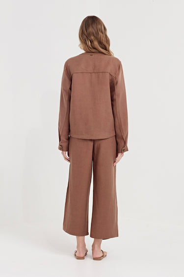 A woman viewed from behind wearing a matching brown long-sleeve top and wide-leg cropped pants set by Verge, standing against a plain light gray studio background.