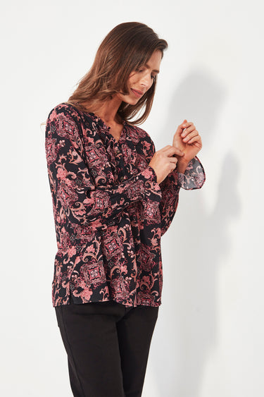 Woman wearing a floral blouse by Verge against a white background