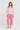 A woman modeling a pink and white striped short-sleeve t-shirt and matching pink cropped pants by Verge, paired with white slide sandals, against a light gray studio background.
