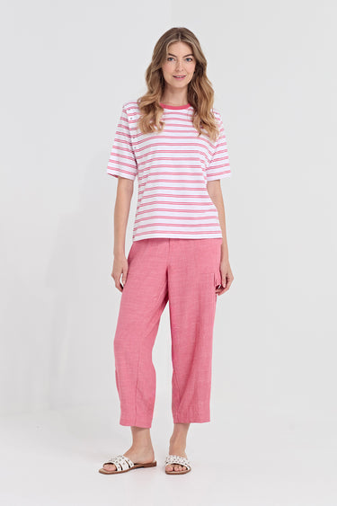 A woman modeling a pink and white striped short-sleeve t-shirt and matching pink cropped pants by Verge, paired with white slide sandals, against a light gray studio background.