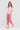 A woman modeling a pink and white striped short-sleeve t-shirt and matching pink cropped pants by Verge, paired with white slide sandals, against a plain white studio background.
