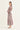 A woman modeling a long-sleeved maxi dress with a dusty rose and beige floral pattern by Verge, standing against a plain off-white studio background.