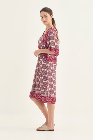 A woman modeling a knee-length printed dress with three-quarter sleeves by Verge, shown in profile against a plain light background.