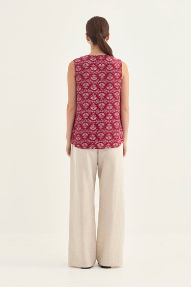 A woman viewed from the back wearing a sleeveless top with a red and white geometric pattern and wide-leg cream pants by Verge, set against a plain white studio background.