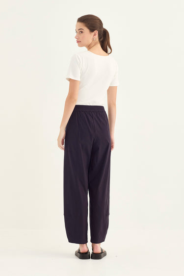 Woman wearing a white top and Midnight Homeland Pants by Verge on a white background