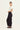 Woman wearing a white top and black Homeland Pants by Verge on a white background