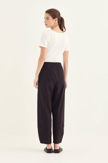 Woman wearing a white top and black Homeland Pants by Verge on a white background