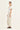 Woman wearing a white top and Putty Homeland Pants by Verge on a white background