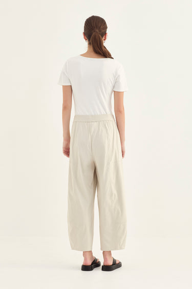Woman wearing a white top and Putty Homeland Pants by Verge on a white background
