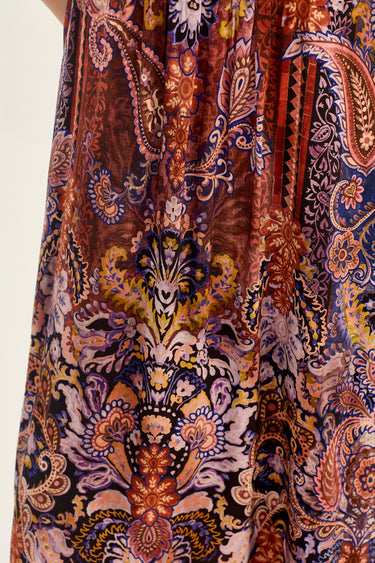 A close-up of a draped fabric by Verge with an intricate paisley and floral pattern in brown, blue, purple, gold, and cream.