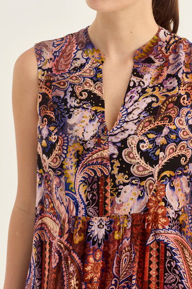 Close-up of a sleeveless V-neck dress by Verge with a busy paisley and floral print in purple, blue, red, gold, and cream tones, shown on a model against a plain light background.