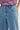 Close-up of a person wearing light blue denim jeans by Verge with a floral-patterned top partially visible at the waist.