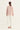 A woman viewed from the back wearing a dusty pink long-sleeve top with a wide ruffled collar and white wide-leg cropped pants by Verge, standing against a plain light background.