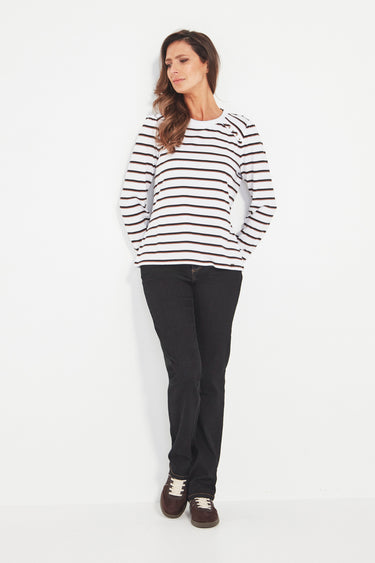 Woman wearing a black and white striped sweater and black pants by Verge on a white background